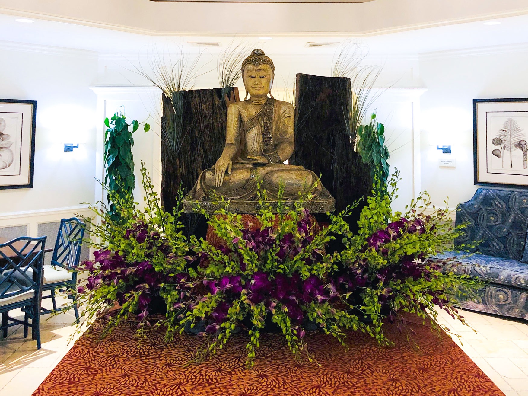Purple and green South Florals floral installation surrounding a seated sculpture in an event venue lounge.