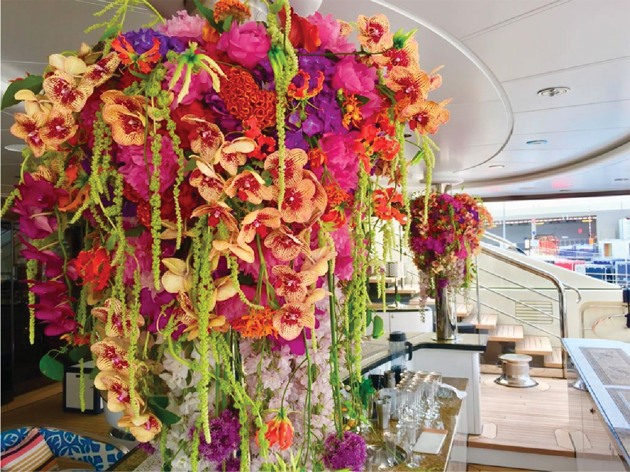 Multicolor orchid installation inside a yacht with the vessel deck visible beyond it.